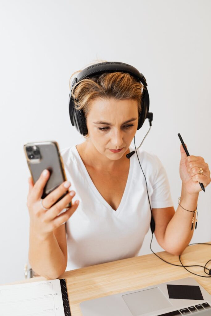 Woman Sitting at the Desk Using a Laptop and a Smartphone