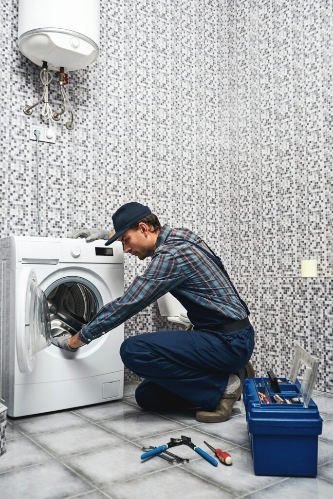 Repair washing mashine atantive. Working man plumber repairs a washing machine