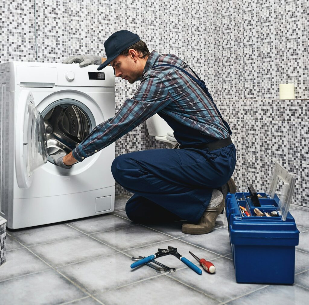 Repair washing mashine atantive. Working man plumber repairs a washing machine